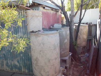 Painted rain barrels with matching cat litter bucket on top under roof drain spout... The cat litter bucket with an upside down planter inside 
	  settles out the dirt and gravel before the overflow fills the rain barrel.